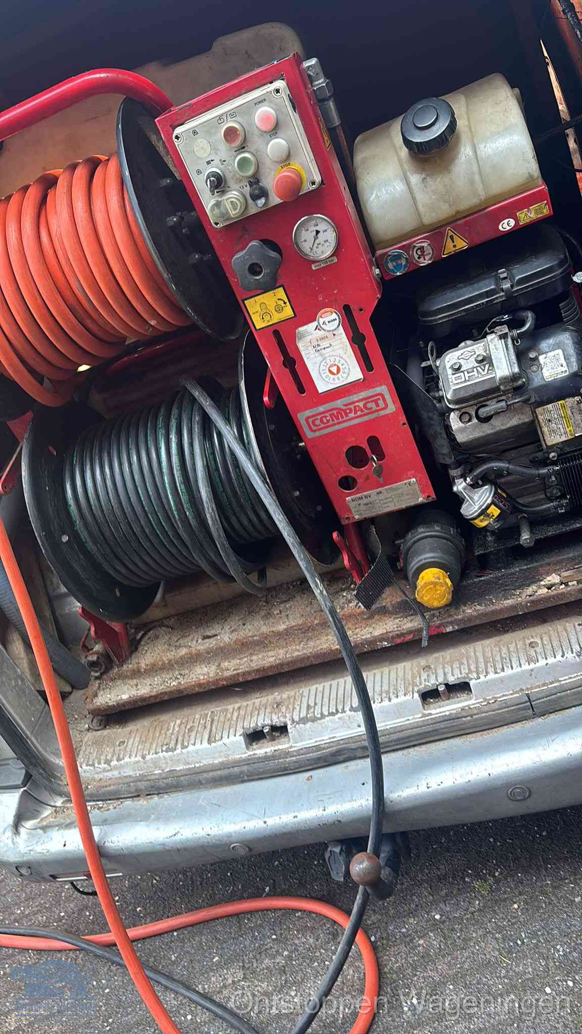 Een rood hogedruk-rioolreinigingstoestel met slangen in de laadbak van de bedrijfsbus, apparatuur voor een hardnekkige wc-verstopping in Wageningen