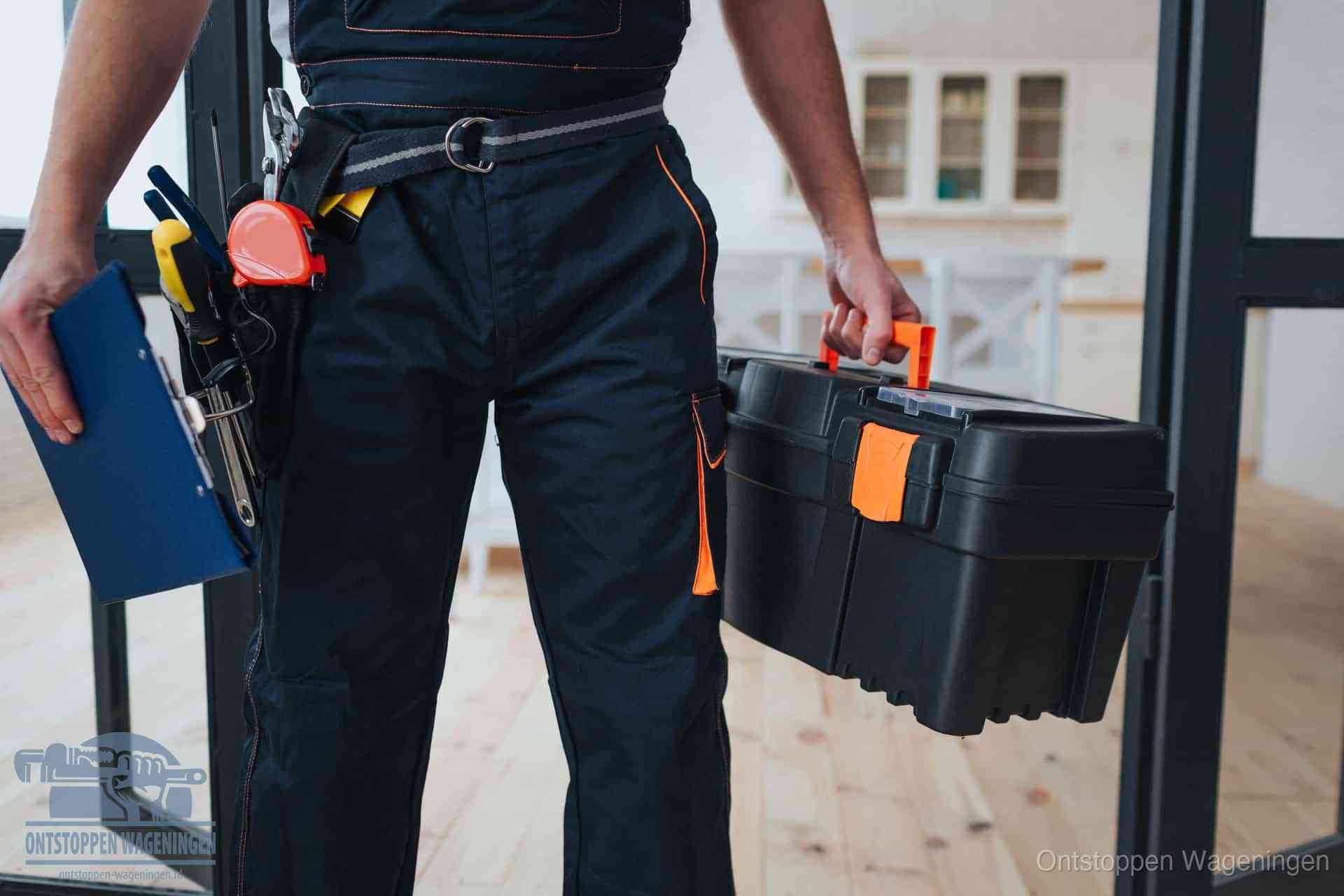 Een monteur met gereedschapsriem en klembord in een keuken, klaar om een transparante prijs voor het gootsteen ontstoppen in Wageningen te geven