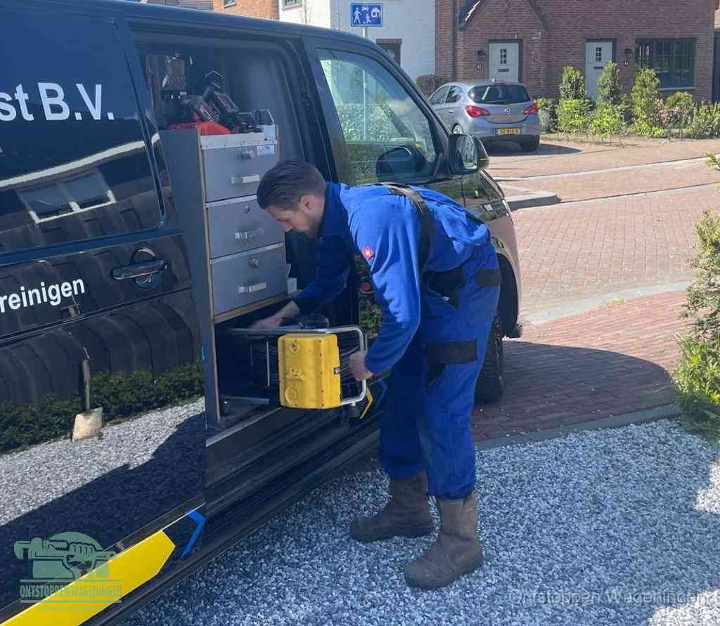 Een monteur pakt buiten op de oprit gereedschap uit de bedrijfsbus, het moment om een professional in te schakelen voor een verstopte afvoer in Wageningen