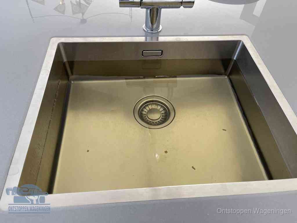 Stilstaand water in een rvs spoelbak dat niet wegloopt, een duidelijk signaal van een gootsteenverstopping in Wageningen