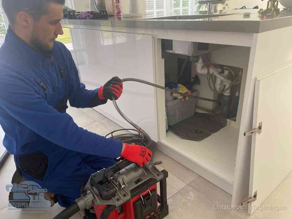 Een monteur reinigt de keukenafvoer grondig met een veermachine om terugkerende gootsteenverstoppingen te voorkomen in Wageningen
