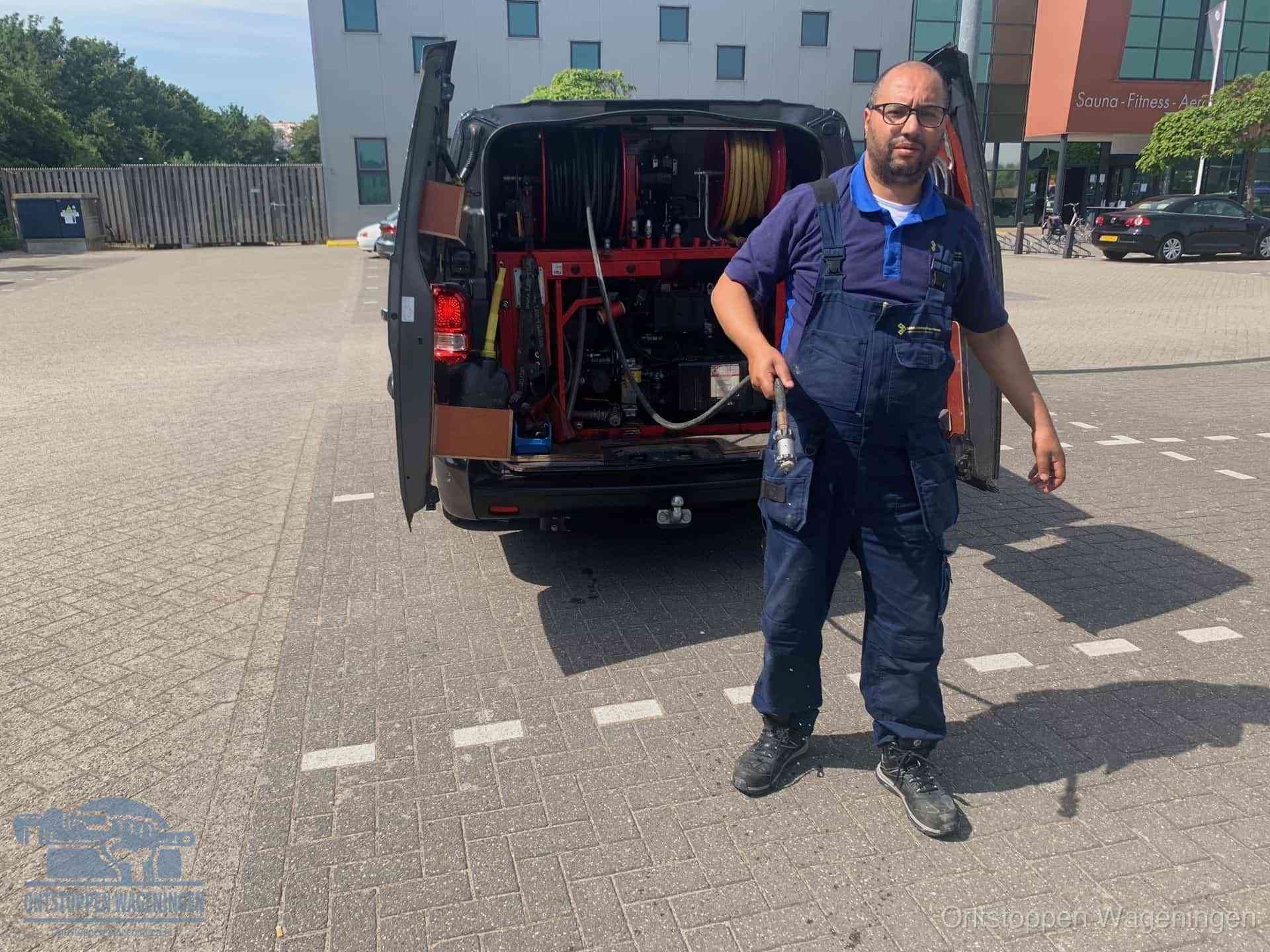 Een monteur bij zijn bestelbus met een hogedruk- en rioolreinigingsunit, klaar om de oorzaak van terugkerende wc-verstoppingen aan te pakken in Wageningen