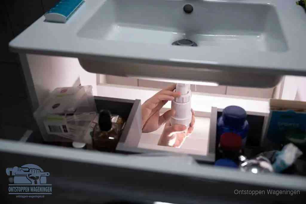 Een pompfles met zeep boven een wastafel in de toiletruimte, de warm water en afwasmiddel-methode om de wc te ontstoppen in Wageningen