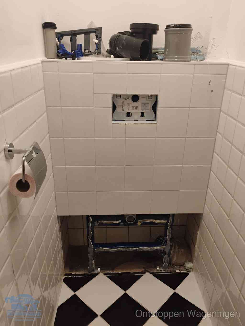 Een toiletruimte waar het hangtoilet en de inbouwreservoir-onderdelen zijn vrijgelegd voor onderhoud, periodiek nazicht voorkomt een wc-verstopping in Wageningen