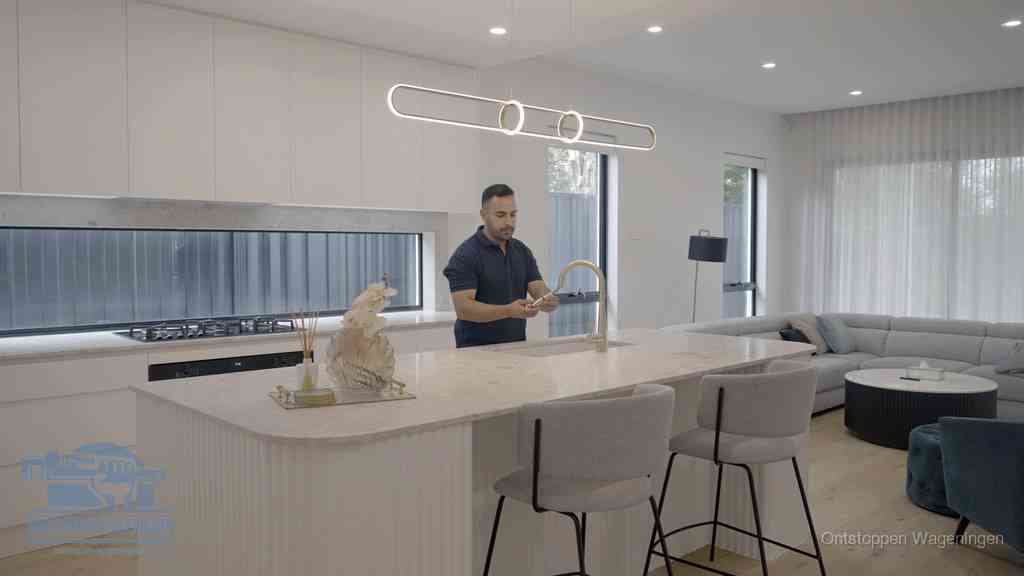 Een bewoner bij de keukenspoelbak die zelf aan de slag gaat met een verstopte gootsteen in Wageningen